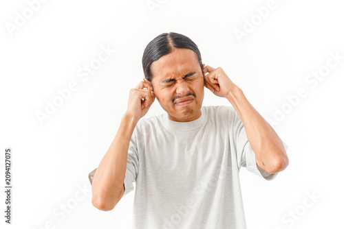Принти на полотні Young Asian man covering ears due to loud noise