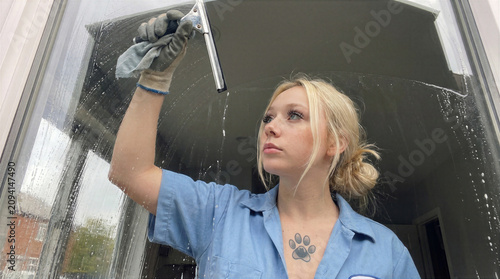 Young Woman Cleaning Window with Glass Cleaner and Cloth