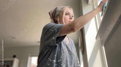 Young Woman Cleaning Window with Glass Cleaner and Cloth