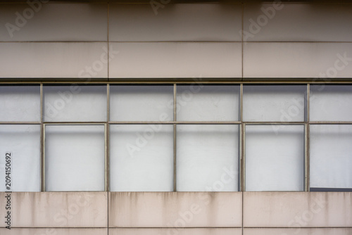Modern building facade with large frosted glass windows and concrete panels creating a minimal geometric architectural background.