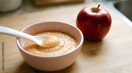 Homemade applesauce with fresh red apple on wooden surface healthy food concept