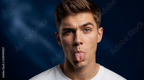 Portrait of a young man making a funny face by sticking his tongue out.