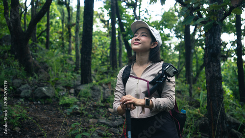 Foto A smiling young Asian woman hiker wearing a backpack with an action camera attac
