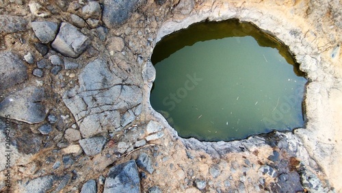 Fotografie natural pool of greenish water nestled within a rugged, rocky terrain