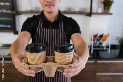 Paper cup coffee barista apron cafe tray drink takeaway service from smiling male server in modern shop interior