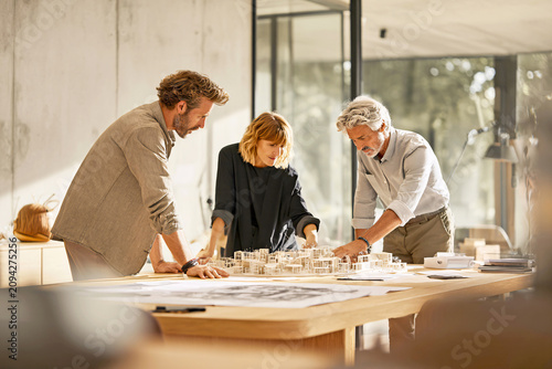 Diverse Team Collaborating on Architectural Model in Bright Modern Office