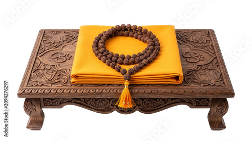 Traditional carved wooden meditation seat with a folded yellow cloth and a rudraksha mala bead necklace, isolated on a transparent background