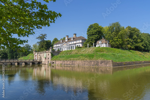 Exterior view of historic Bad Pyrmont Castle with moat and park in summer