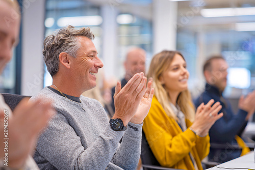 Businesspeople applauding in modern office setting with happy expressions