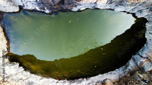 Obraz na plátně The image shows a natural rock pool filled with greenish, murky water