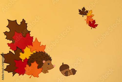 Cuadro en lienzo Creative decoration showing a hedgehog with colorful leaves and an acorn on a pl