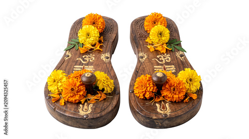 Traditional carved wooden Guru paduka sandals adorned with fresh orange and yellow marigold flowers, isolated on a transparent background
