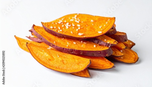 Stacked roasted sweet potato wedges with salt and pepper on white surface under soft light.
