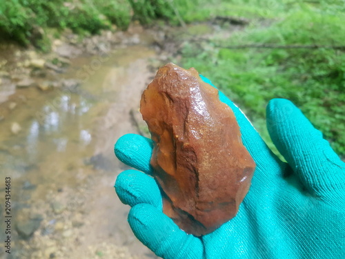 Billede på lærred Flint stone resembling an ancient hand axe held in a gloved hand, discovered dur