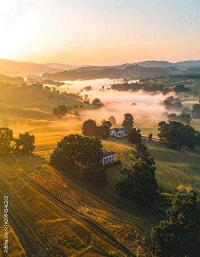 Sunrise illuminates a misty valley with historic homes nestled in rolling hills.