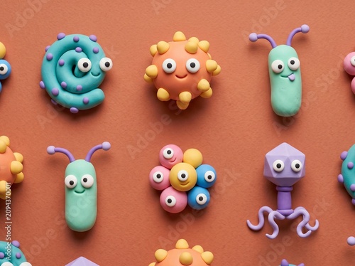 Handcrafted polymer clay microorganisms are arranged in rows on a flat surface