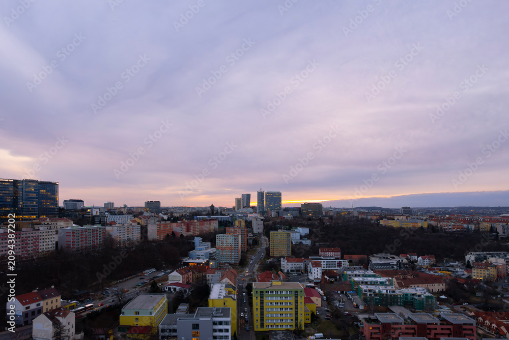 Obraz premium Aerial view of Prague's Michle district with V Tower on the horizon during a colorful winter sunset. Urban residential and business architecture captured from a drone without snow.