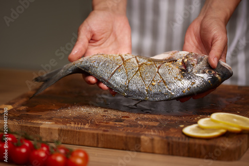 Chef hands holding seasoned sea bream ready for cooking