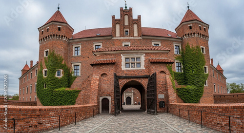 Majestic red brick medieval fortress stands prominently with its imposing gatehouse and crenellated towers, showcasing centuries of architectural grandeur and historical significance under