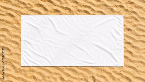 Top-down flat lay of a blank white beach towel mockup spread out on ribbed golden sand