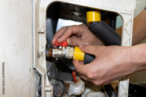 Plumber hands adjusting pipe fitting with yellow protective caps, professional heating or water system installation work, close up view of technical maintenance.
