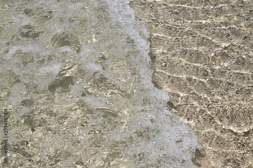 Waves on the summer sand beach with fresh clear water. 