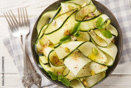 Foto Zucchini carpaccio is a fresh, crisp, and low-calorie appetizer topped with pistachios, chili pepper, and mint