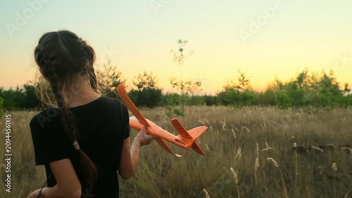 Kid with toy plane is playing at sunset.