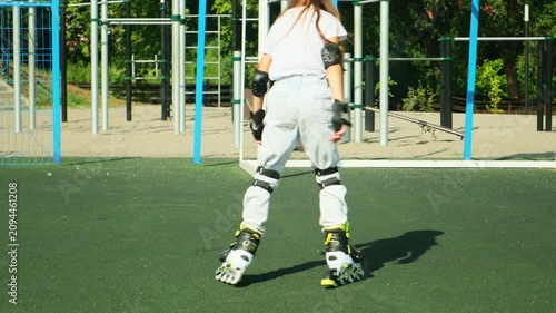 Little girl on roller skates in helmet at a park. Child in protective sportswear