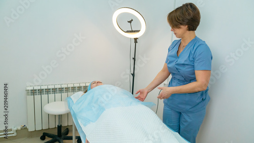 Foto positive professional masseuse in a cozy massage room with a female client lying