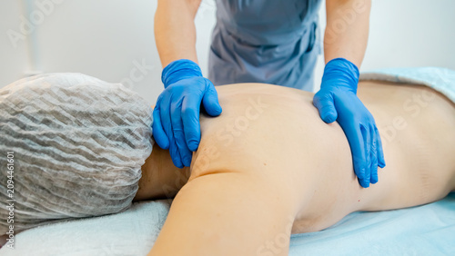 massage therapist gives a massage to a patient back on a massage table at a clinic. Works with back injuries and spinal problems.