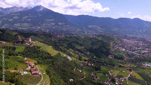 Castel Tirolo South Tyrol Italy 4K Drone. Far pull back turn to valley view with epic alpine mountain background. Long distance aerial panoramic flight medieval castle b-roll cinematic video asset