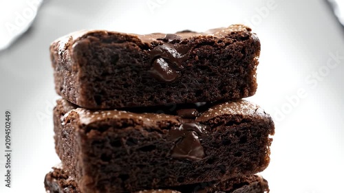 Three Stacked Chocolate Brownies With Icing Sugar On White Background