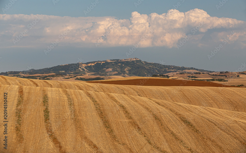 Obraz premium Harvested Fields with Medieval Hilltop Village and Storm Cloud, Tuscany Italy