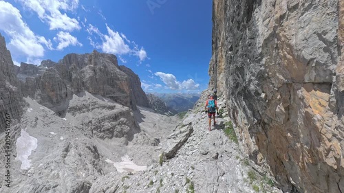 Two hikers traversing the spectacular ledge of Via Ferrata Bocchette Centrali in the Brenta Dolomites