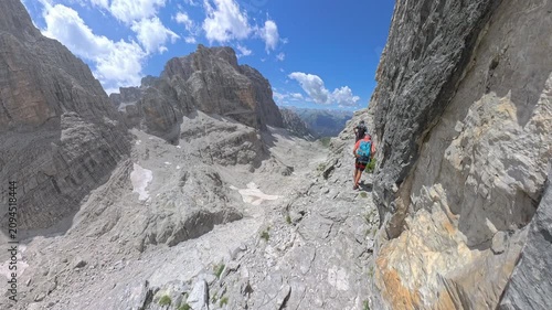 Two hikers crossing an exposed cliffside ledge on Via Ferrata Bocchette Centrali, Brenta Dolomites