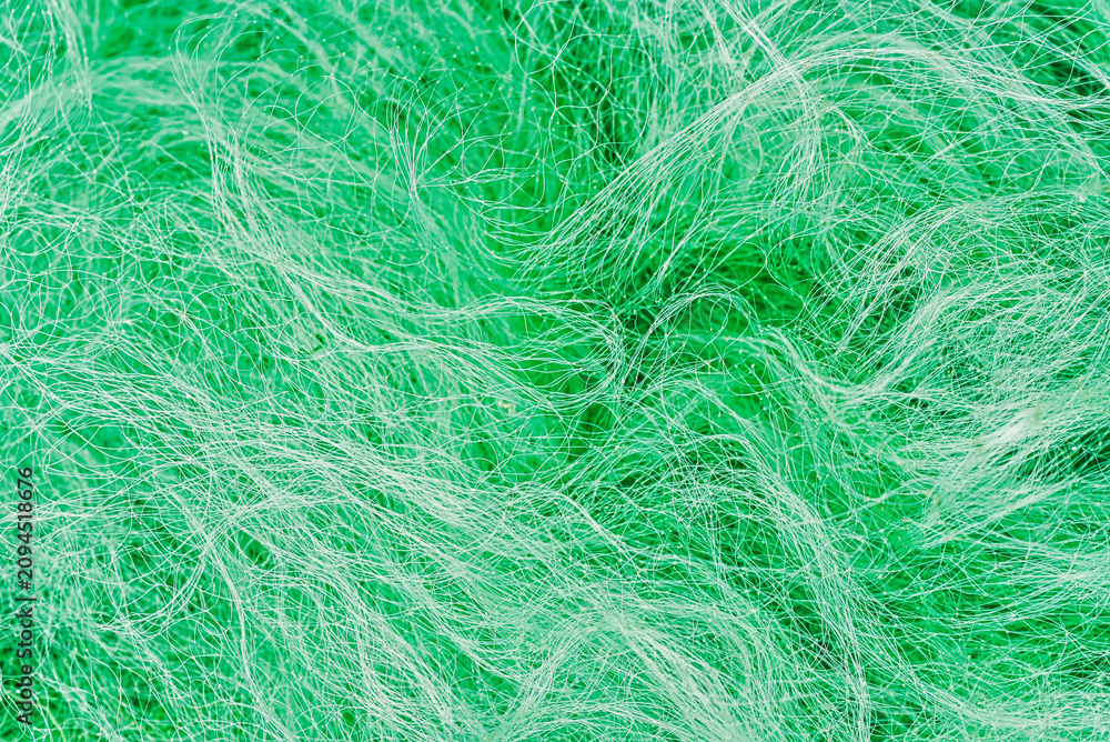 Obraz premium Close-up texture of a green nylon fishing net with tangled fibers and intricate woven patterns. 