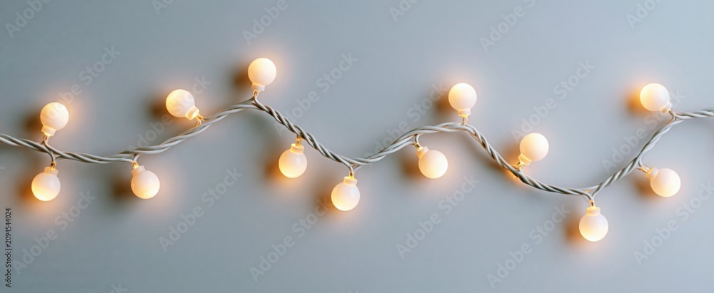 Fototapeta premium Cozy white Christmas garland lights shimmer gently on a simple winter backdrop for holiday cheer