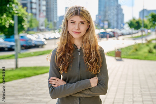 Portrait of beautiful confident young blonde woman looking at camera on modern city street