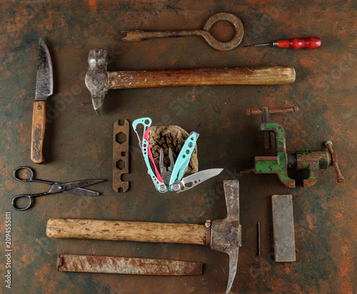 Top view of a modern bright multitool over vintage tools.