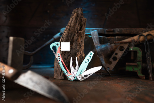 Modern multitool with vintage tools on a dark wood background.