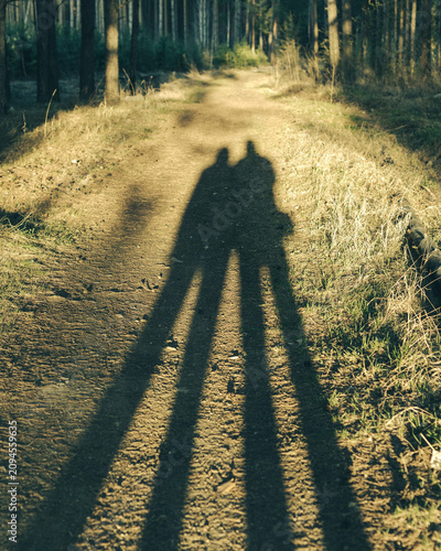 Sunset Hug, Long Shadows of a Couple on a Woodland Path