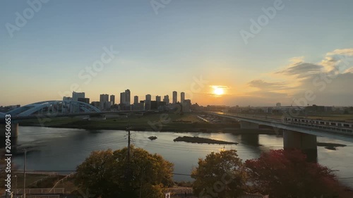 Warm sunset reflecting on the Tama River with a view of the Kawasaki city skyline and bridges