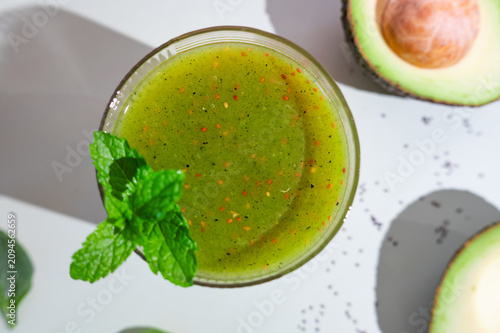Green superfood smoothie with avocado, spinach, and chia seeds, vegan wellness drink.