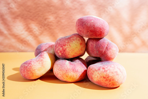 Fresh ripe fig peaches arranged in a pile on a vibrant yellow background, summer fruit concept.