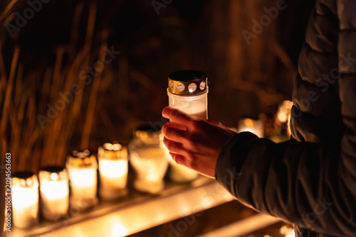 Fotografie person holding lit memorial candle outdoors at night during All Saints Day in St
