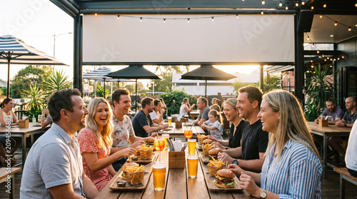 Group friend restaurant patio meal beer summer outdoor dinner gathering enjoying cheerful conversation at long table with food and drink during sunset