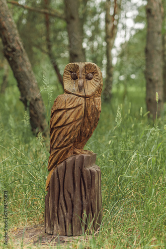 Beautiful wooden owl sculpture carved from tree trunk in forest
