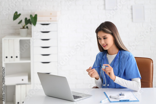 Female doctor with glucose sensor giving online consultation in clinic