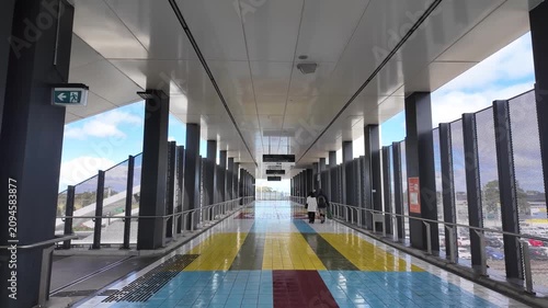 Commuters walk through a covered pedestrian overpass at Hoppers Crossing railway station, Melbourne Australia. Public transport infrastructure, commuter access and everyday suburban life
